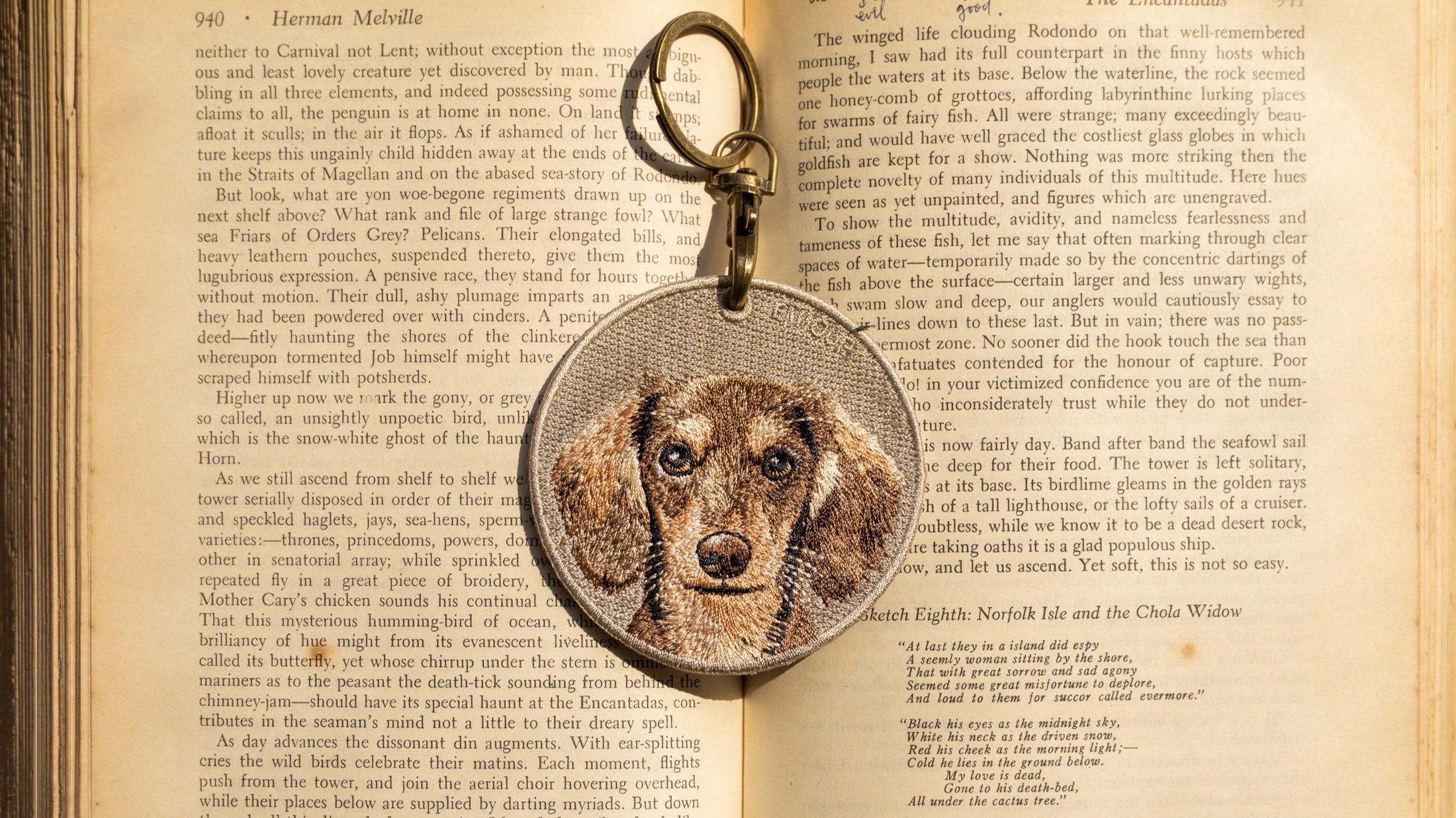 Embroidered dog keychain photographed on an open book