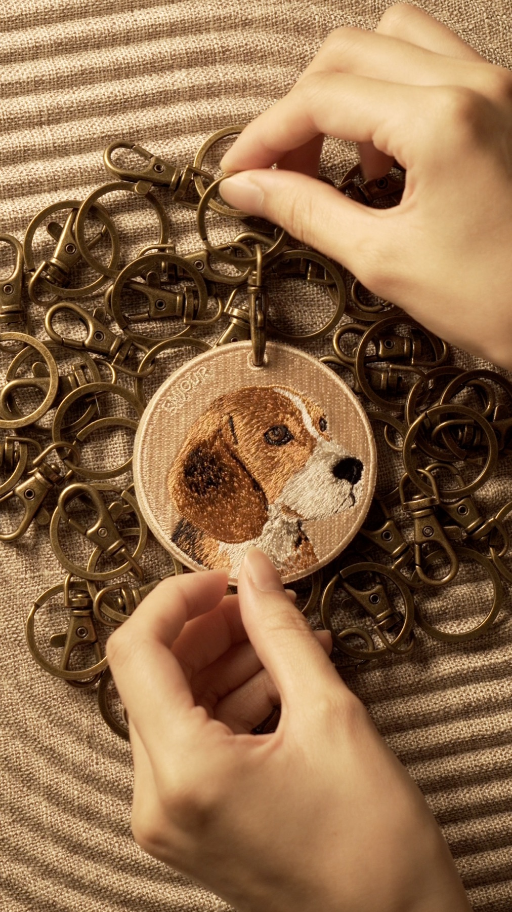 Hands presenting an embroidered dog keychain