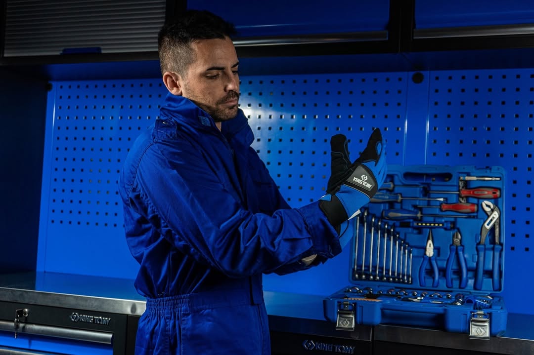 Mechanic putting on King Tony work gloves beside a tool cabinet
