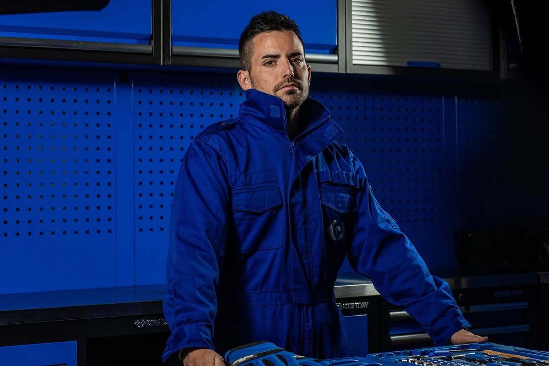 Mechanic in blue King Tony workwear standing inside a tool workshop