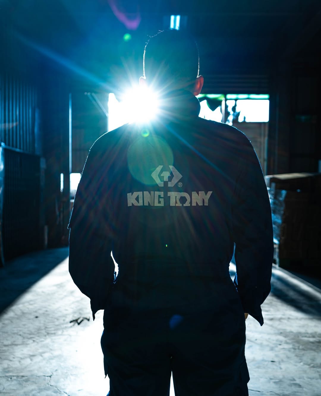 Backlit mechanic wearing King Tony workwear inside a workshop