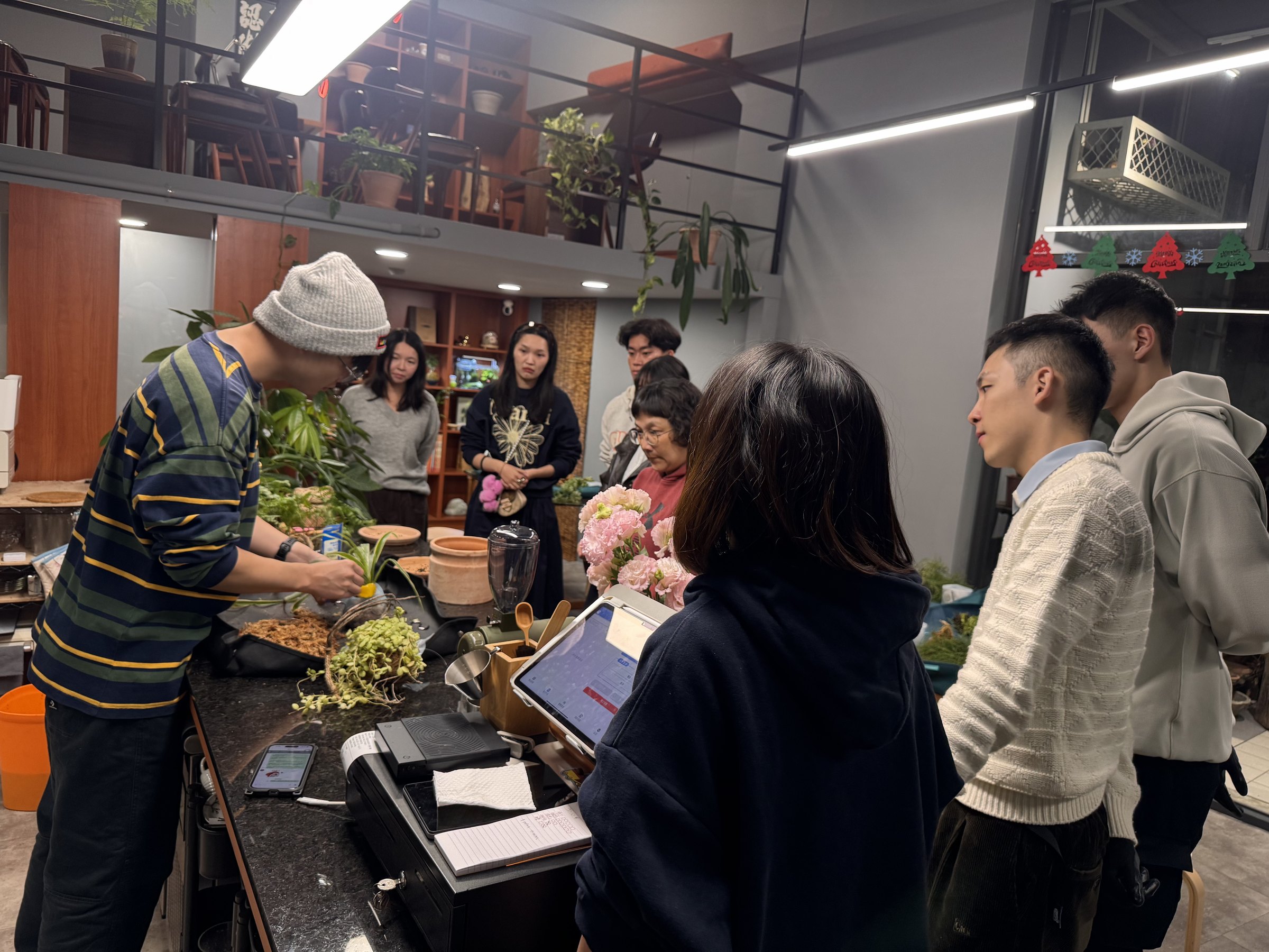 A group watching a hands-on plant workshop at the Plants Cafe counter