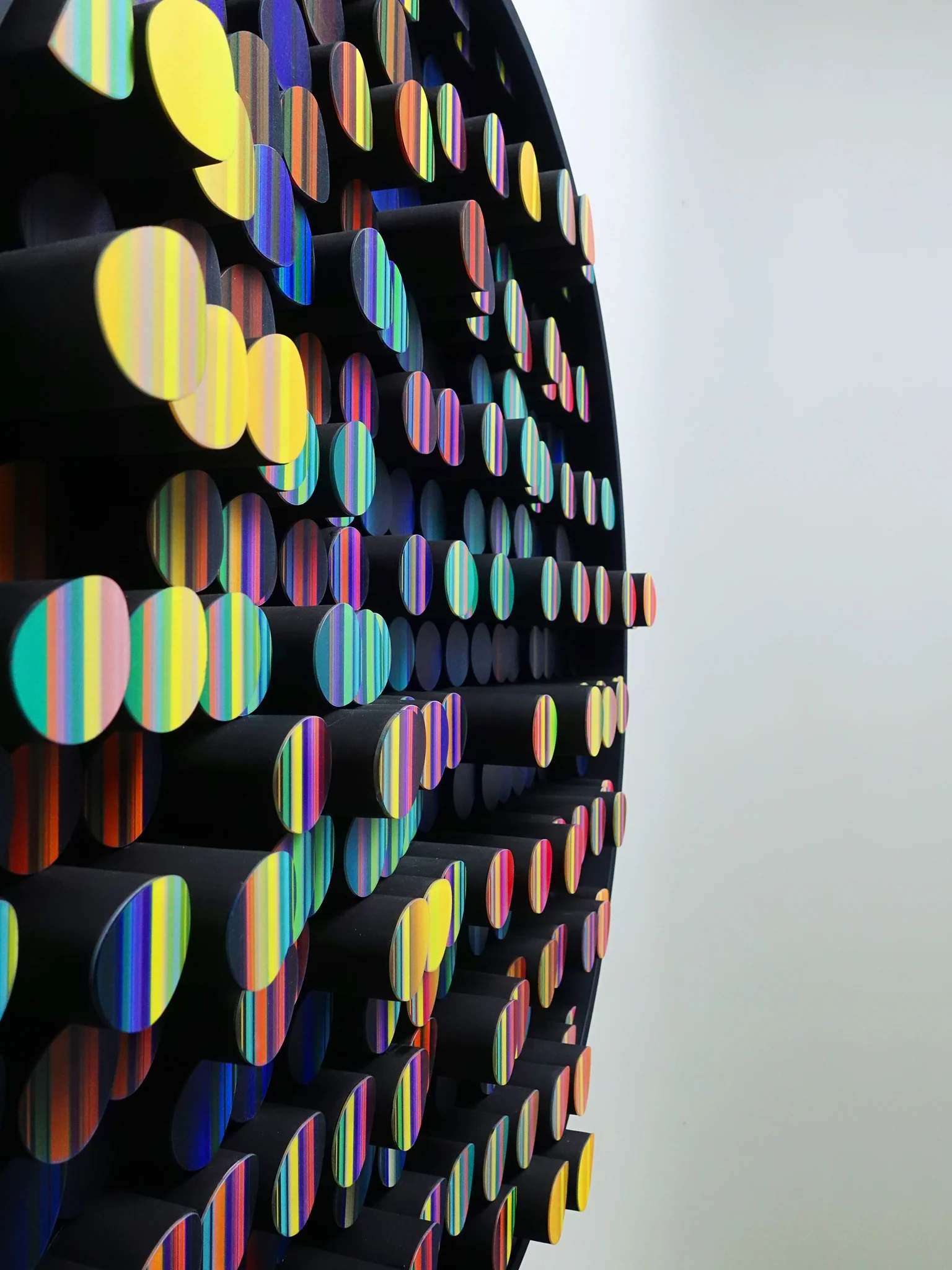 Side view of colorful textile elements projecting from a circular artwork